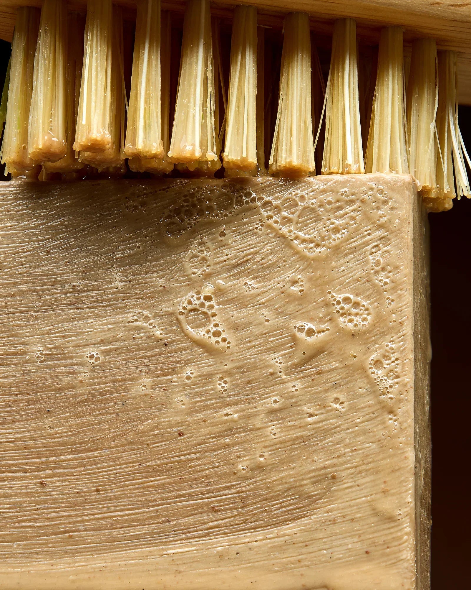 Gros plan sur un savon d'Alep humide et moussant à côté d'une brosse en fibres naturelles — Al Bara