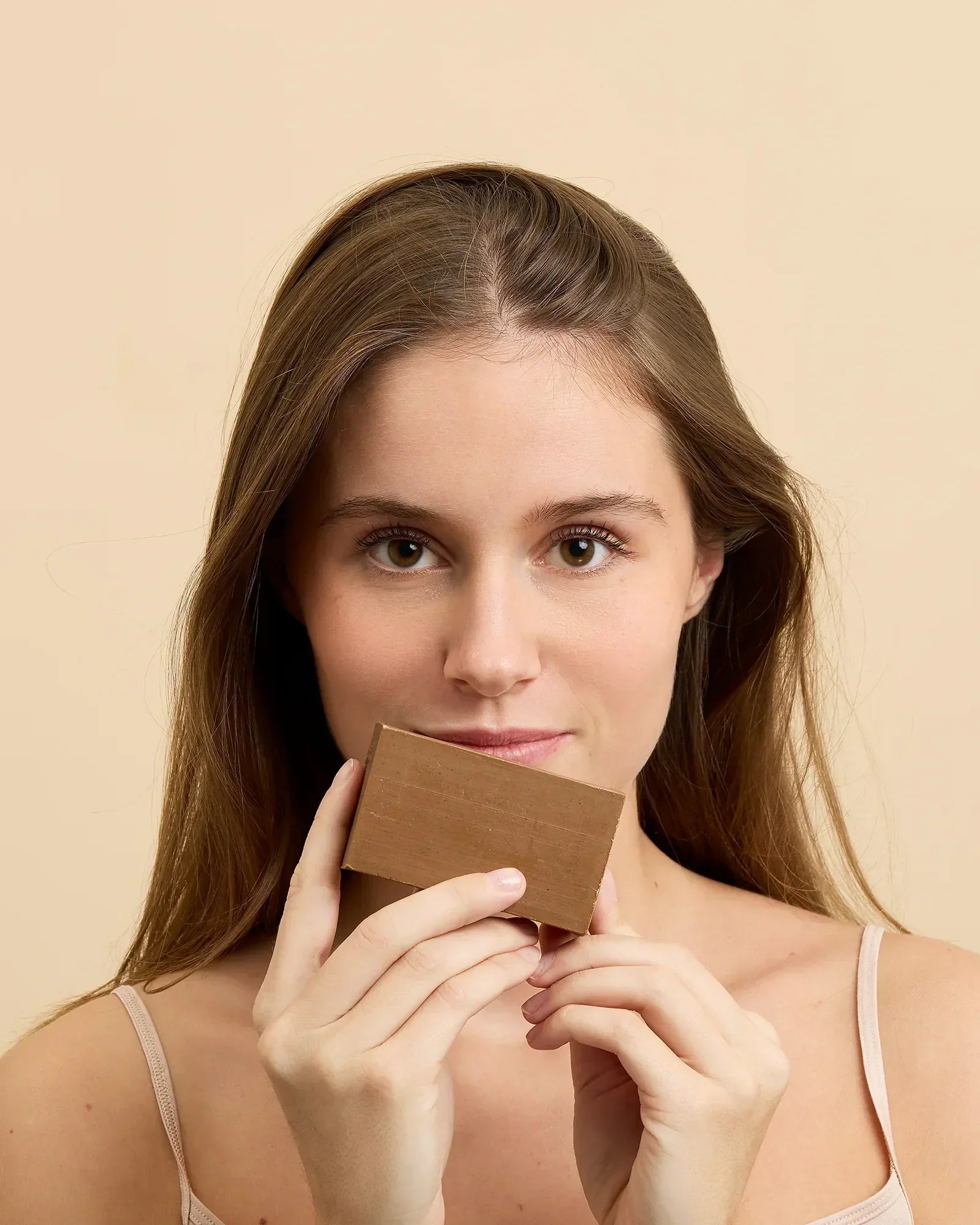 Savon d'Alep à l'argile rose tenu près du visage, soin purifiant peau sensible — Al Bara