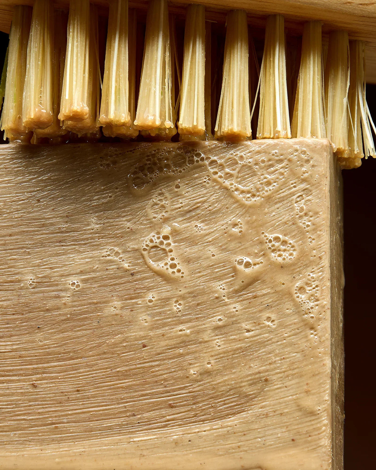 Gros plan sur un savon d'Alep humide et moussant à côté d'une brosse en fibres naturelles — Al Bara